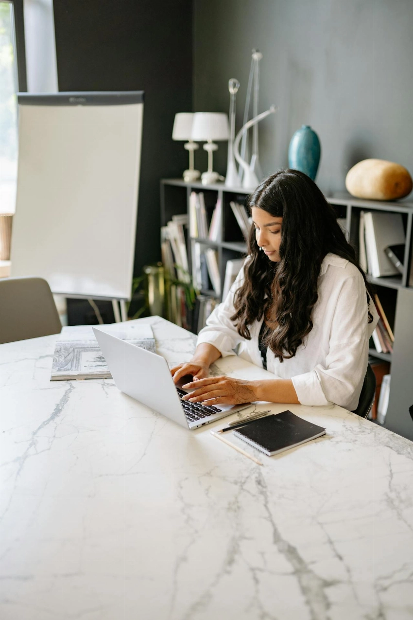 Businesswoman working on a laptop at a modern office desk. Ideal for workplace and productivity themes