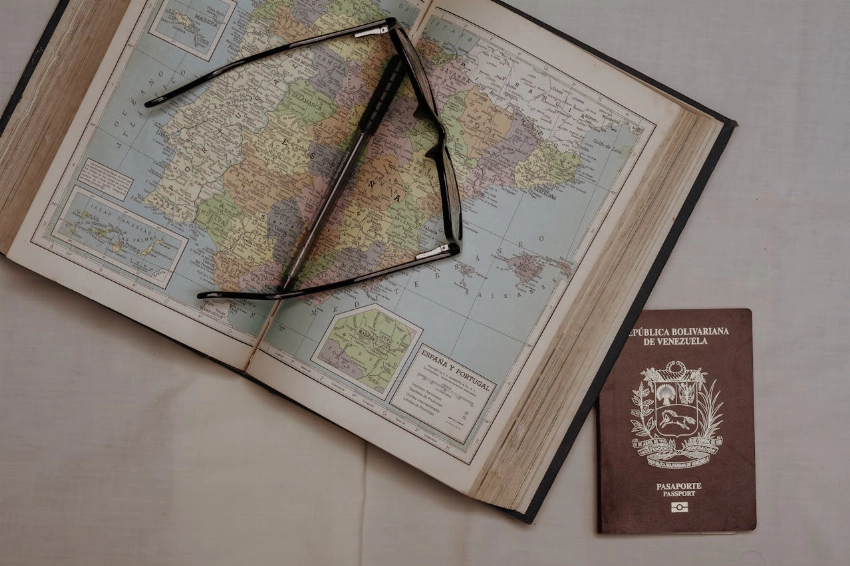 A vintage map of Spain with eyeglasses and a Venezuelan passport, symbolizing travel planning