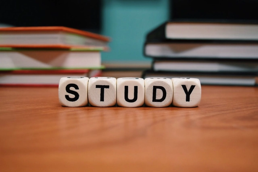Close-up of study blocks and stacked books on a wooden desk, symbolizing education and learning