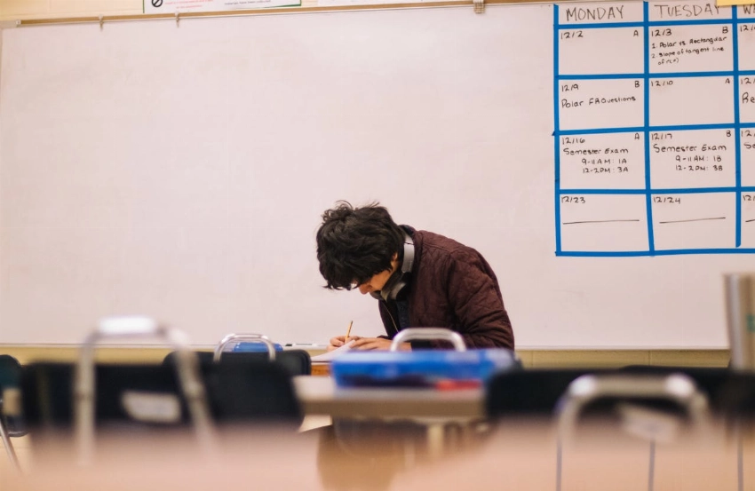 A high school student studying and solving problems in a classroom setting
