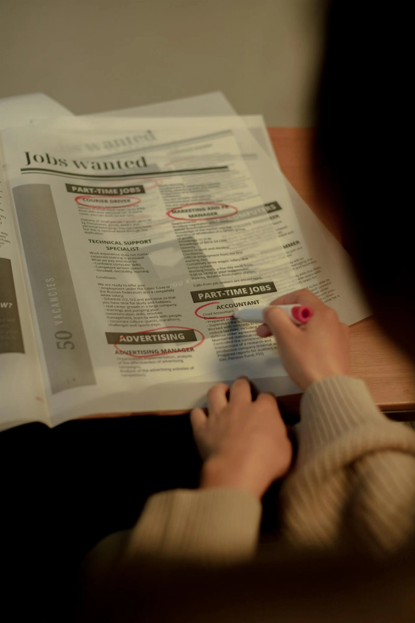 Close-up of a person marking job listings in a newspaper indoors