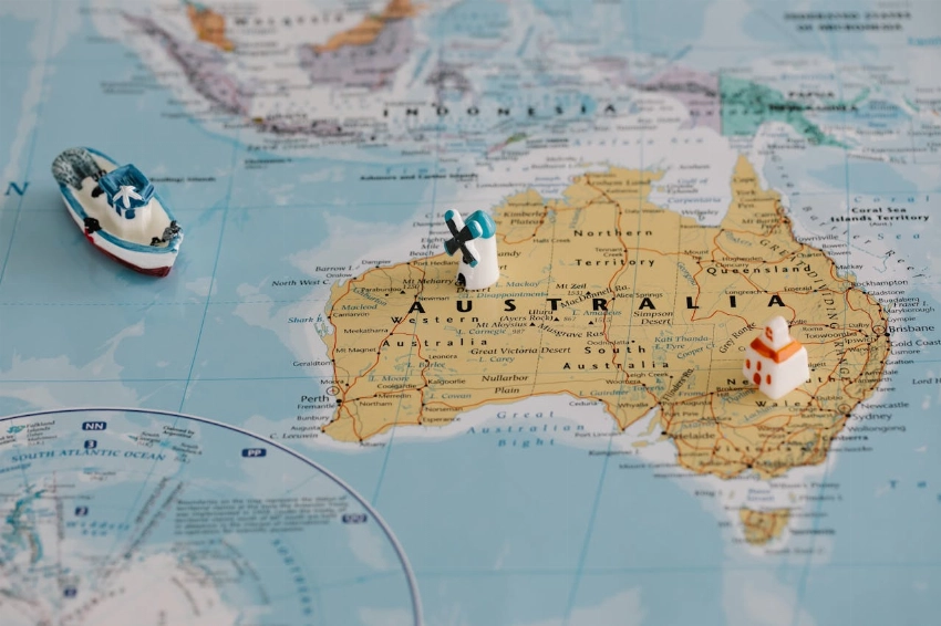 Miniature windmill and ship placed atop a map of Australia, highlighting travel concepts