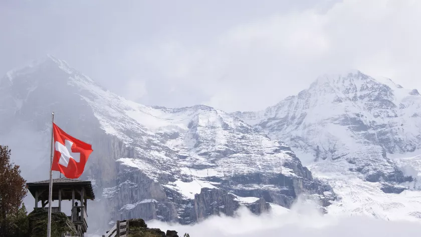 Swiss flag with alps in the background