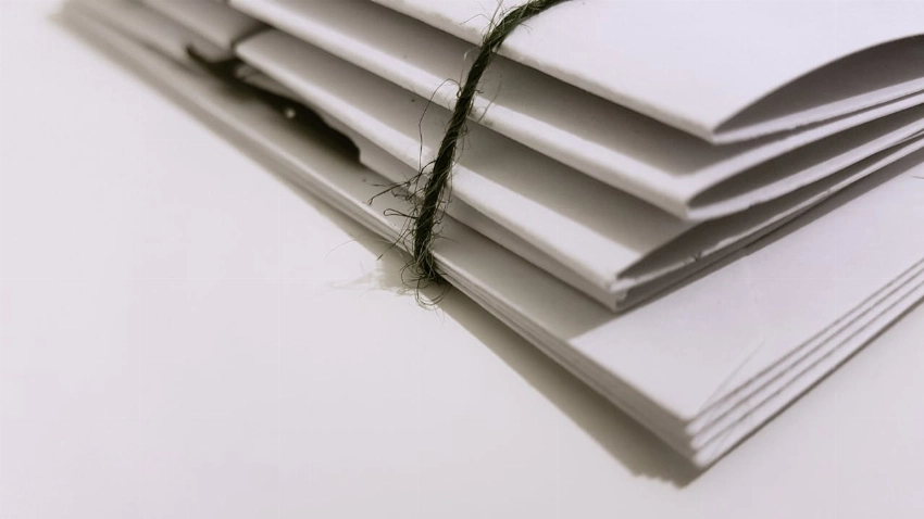 Pile of white envelopes tied with a green string, showcasing a minimalist design