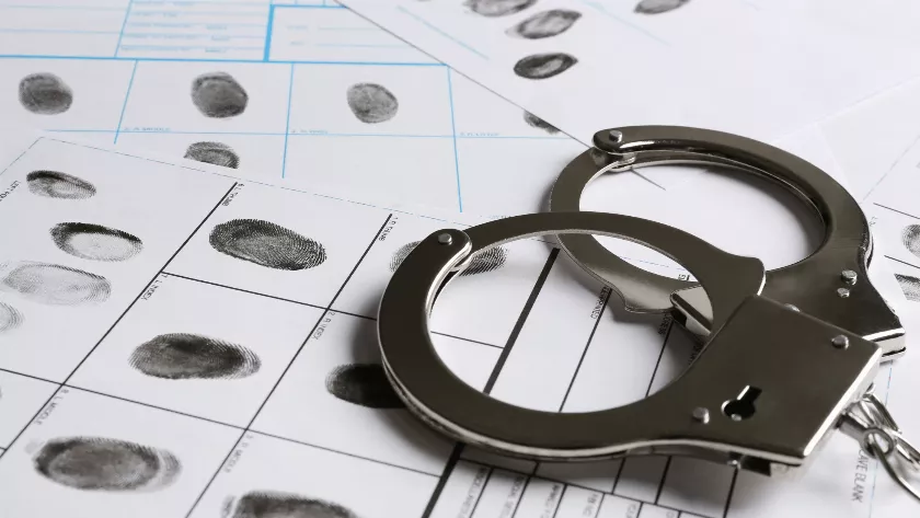 Handcuffs on the top of some papers with fingerprints